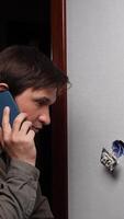 A man talking on a cell phone while looking at a wall video