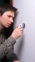vertical tired man looking at broken electrical switch, electrical wiring. Man tired of repairing apartment. Sad man with depressed mood can't fix socket, electrical wires video