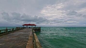 A picturesque view of a pier extending into tranquil ocean waters, framed by dramatic clouds in the sky, perfect for relaxation. video
