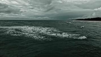 A dramatic scene of dark, stormy waters showcasing rolling waves under a cloudy sky at dusk, highlighting nature's wild beauty. video