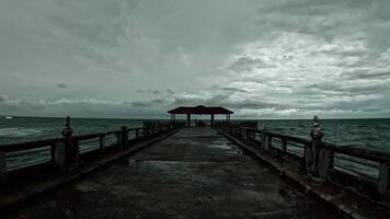 A captivating scene showcasing a weathered pier extending into a turbulent ocean under a cloudy sky, evoking feelings of solitude and adventure. video