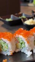 Sushi platter with assorted rolls, fish roe, sesame, sauce and ginger, slow motion table shot video