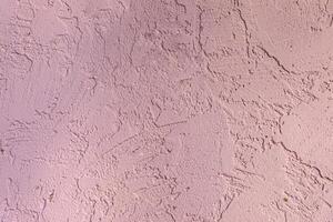 Textured light pink stucco wall with natural rough patterns, ideal for use in backgrounds, design, or architectural visuals. photo