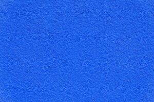 Close-up of a rough blue painted wall with subtle texture, ideal for backgrounds, design mockups, or architectural use. photo
