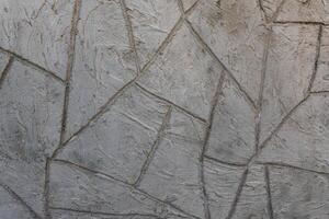 Detailed view of a gray plaster wall with geometric trowel patterns and rugged texture, suitable for architectural and design backgrounds. photo