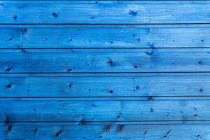 Horizontal planks of wood painted in bright blue with visible grain and knots in natural light. photo