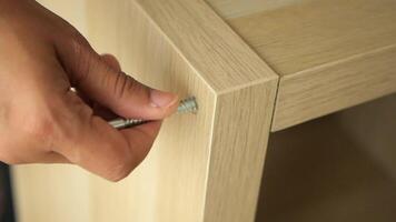 Assembling furniture with a screw, wood, and tools video