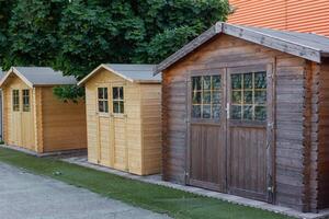 Wooden garden sheds displayed on artificial grass with tree in background photo
