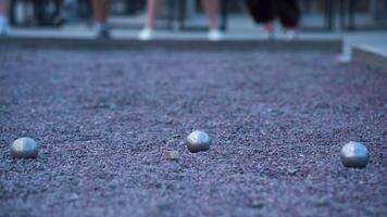 Throwing metal balls in a game of petanque on a rubble court video