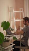 A young man is situated comfortably at his modern workspace, where he takes a moment to stretch and relax while using his laptop, perfectly capturing a serene and enjoyable remote work atmosphere video