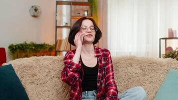 Young woman talking on smartphone, smiling with joy and using expressive hand movement during call video