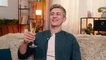 Young man lifts champagne glass and smiles confidently while making toast and celebrating success video