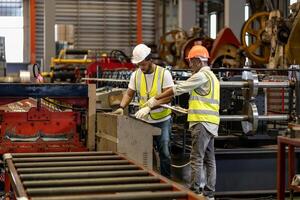 Team of African American industrial worker is calibrating the setup values of metal sheet roll forming machine by automated monitor while working inside roof factory for safety industry concept photo