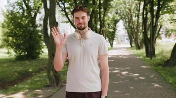 Athletic fit runner guy waving hi hello, welcome with palm greeting with hospitable friendly smile video