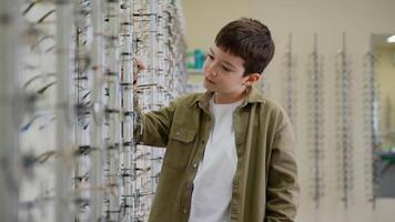 Boy choosing eyeglasses in optical store video