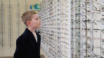 Young boy choosing eyeglasses in optical store video
