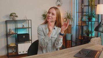 Happy woman claps hands and shows thumb up gesture congratulating on victory at home table desk video