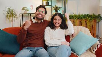 Indian couple celebrating success clenching fists showing thumbs up and giving high-five at home video
