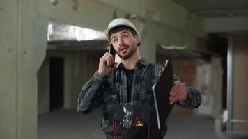 Caucasian man builder architect call mobile phone male engineer in helmet work at construction site control building process foreman industrial worker talking cellphone command architecture project video