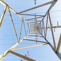 Symmetrical view up steel power tower against blue sky photo