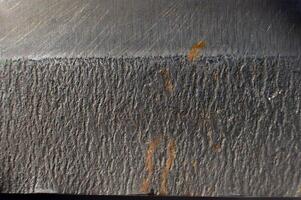 Close-up of the textured surface of a kitchen knife with rust stains. Macro shot of metal surfaces photo