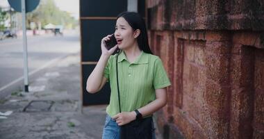 Handheld shot, Cheerful young woman talks on the phone while walking on a sidewalk in the city. video