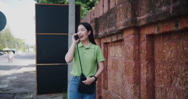 Handheld shot, Cheerful woman happily talks on the phone while walking on a sidewalk in the city. video