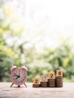 Pink alarm clock, Wooden blocks with the number 2026 on stack of coins. The concept of saving money for manage time to success business in year 2026 photo