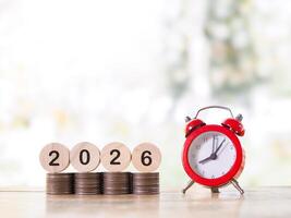 Red alarm clock, Wooden blocks with the number 2026 on stack of coins. The concept of saving money for manage time to success business in year 2026 photo