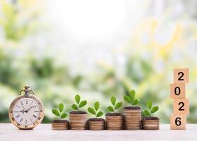 Vintage watch, Wooden blocks with the number 2026 and plants growing up on stack of coins. The concept of saving money for manage time to success business in year 2026 photo