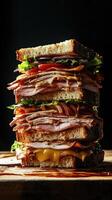 Indulgent towering sandwich stacked high with layers of turkey, cheese, and fresh vegetables in a moody kitchen setting photo