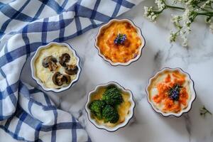 Mini casseroles featuring broccoli with cheddar, mushrooms with sun-dried tomatoes, and egg with salmon served on a marble countertop photo