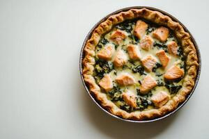 Perfectly styled open salmon pie with wilted spinach and creamy lemon filling on a clean white background and soft natural lighting photo