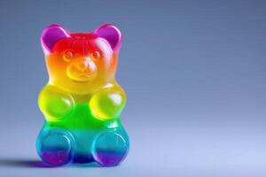 A large, brightly colored gummy bear sits prominently against a smooth, neutral backdrop. The vibrant hues transition smoothly, showcasing its playful design and inviting appearance. photo