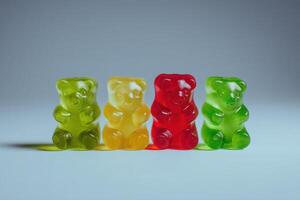 Four gummy bears displayed in a row, featuring yellow, red, green, and a lighter green color. The bears sit on a smooth surface, illuminated by soft background light that enhances their transparency. photo