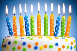 A beautifully decorated birthday cake showcases brightly colored candles in blue, orange, and green, each topped with a flame, surrounded by cheerful polka dots, celebrating a joyous occasion. photo