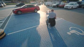 Man with disabilities in wheelchair pushing cart in front of himself at supermarket parking 10 video