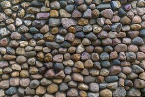 Wall fence of stones of different sizes roughly stacked on top of each other and fastened with cement. Construction industrial background. photo