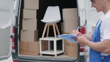 Two young workers of removal company are loading boxes and furniture into a minibus 49 video