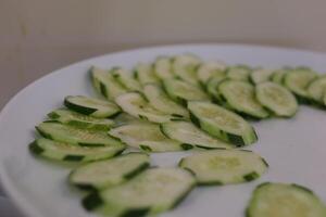 sliced cucumbers rotating on black plate, centered with strong reflection photo