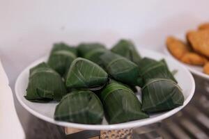Banana leaf wrapper rotating on isolated white Fresh crabs neatly bundled in banana leaves, displayed for sale at a local market, highlighting traditional seafood preparation. photo