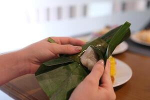 Traditional cake wrapped in banana leaves shaped like a cone, called Mendut cake, filled with grated coconut photo