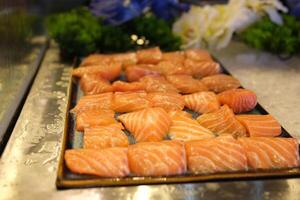 Traditional Norwegian fresh salmon in slices with lemon slices served as close-up on a Nordic design tray with text space photo