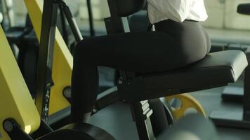 The girl sits down on the training machine and prepares for sports exercise video