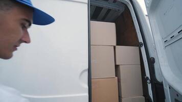 dois jovem trabalhadores do remoção companhia descarregar caixas e mobília a partir de mini onibus para dentro clientes casa 13 video