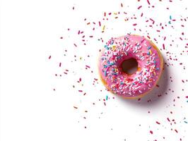 Sweet pink donut topped with colorful sprinkles on a white surface photo