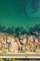 zenithal aerial drone view of a rocky coastline with a wooden pedestrian footbridge, background for summer concept photo