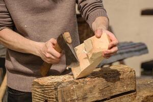 detail of hands using a chisel on wood, a craftsman works on a piece of wood with a small axe photo