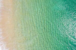 shore of a beach with pristine turquoise waters and golden sand. Overhead aerial view with drone, background for tropical summer concept. photo