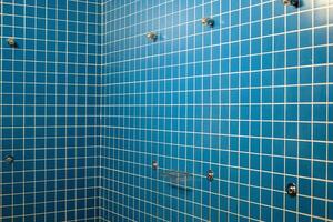 empty shower cubicle interior with white grout lines in a gym photo